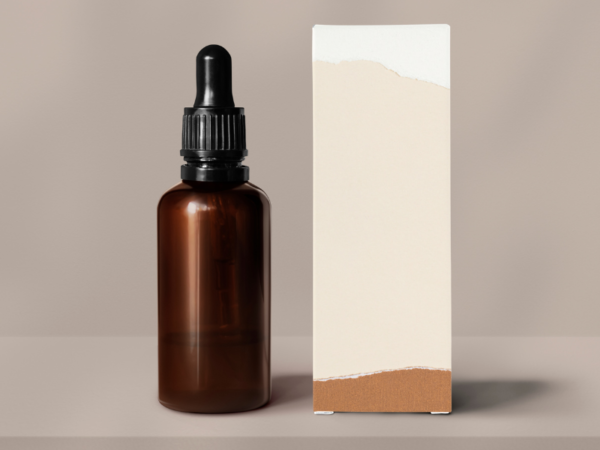 A glass bottle with dropper (an example of primary packaging) next to an outer cardboard box (an example of secondary packaging)